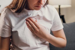 A woman putting her hand to her chest as she experiences a panic attack.