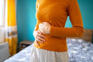 A woman holding her stomach due to pain from endometriosis.