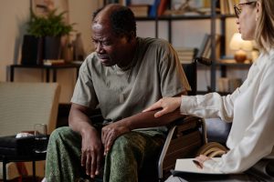 An older man experiencing receiving trauma support from a therapist.