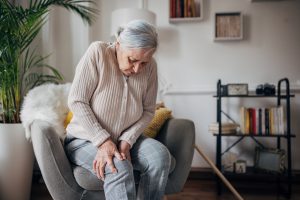 An old woman holding her knee due to arthritis pain.