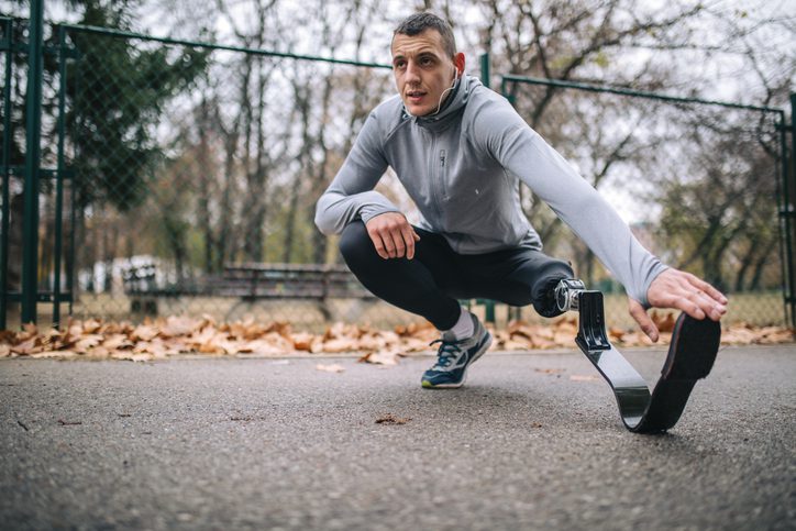 Young and athletic man with a artificial leg, exercising outdoors, living a healthy lifestyle recovering.